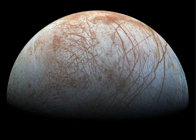 这是木卫二，一颗冰冻卫星。科学家们相当确信，其厚厚的冰层下方是一个巨大的冰下液态水海洋。里面会有生命存在吗？